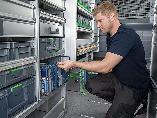 Ein Mann öffnet eine Schublade in einem Handwerkerfahrzeug