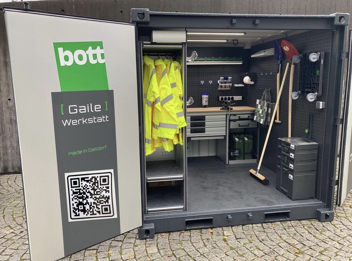  Geöffneter Container einer mobilen Werkstatt, ausgestattet mit Werkzeugen, gelben Warnwesten, Regalen und Schränken